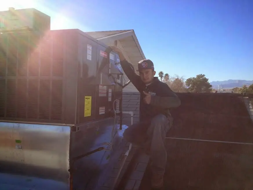 HVAC technician performing Air Duct Repair on a rooftop unit in Logan